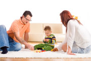 Une famille sur un tapis joue avec son bébé